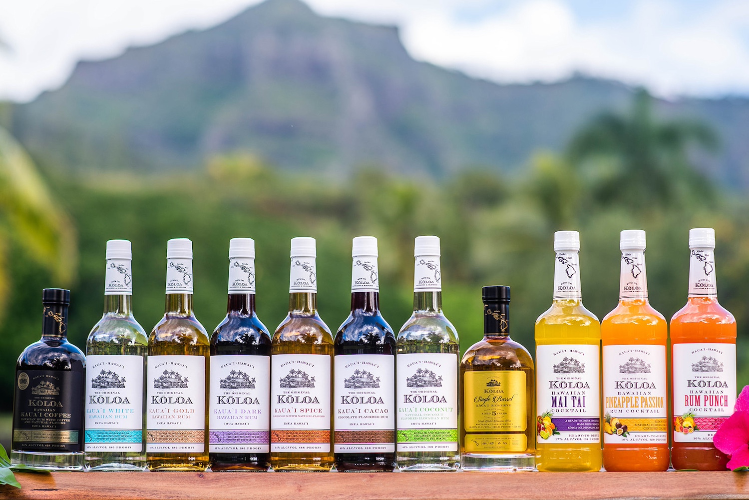 Kōloa Rum's line of spirits and ready-to-drink cocktails on a table in front of a mountain — sustainable rum